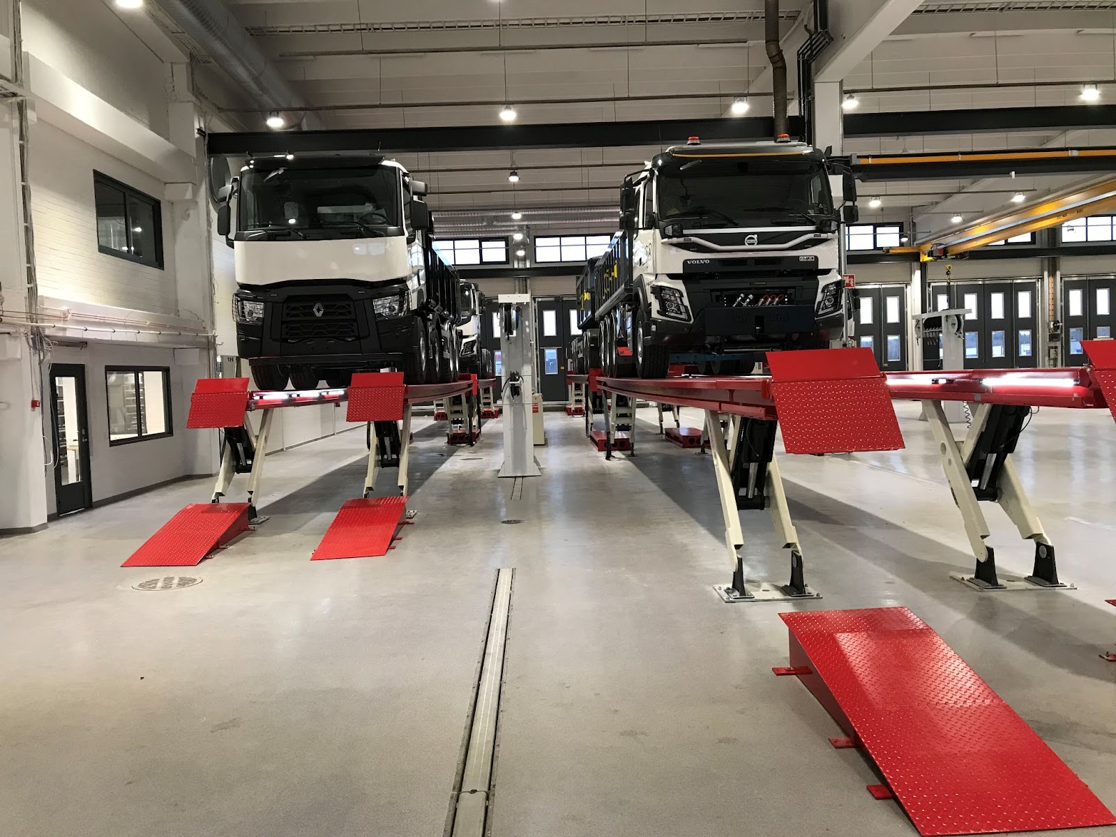 A facility with two different lengths of SKYLIFTs. There are several commercial trucks on the heavy-duty lifts in the facility. 
